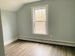 bonus room featuring light wood-type flooring, a baseboard heating unit, lofted ceiling, and plenty of natural light