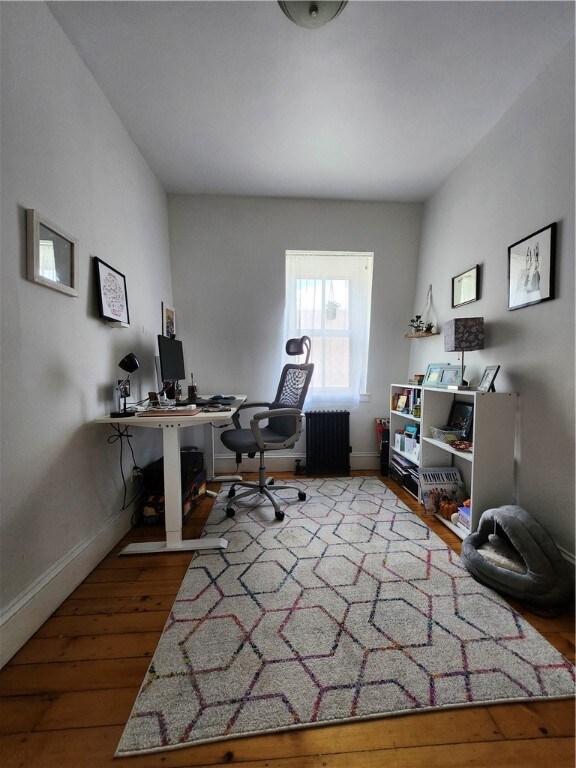 home office with radiator heating unit and wood-type flooring