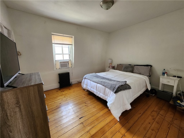 bedroom with cooling unit, light hardwood / wood-style floors, and radiator