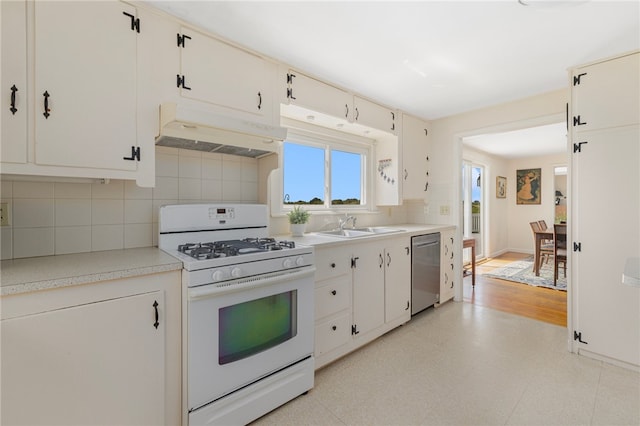 kitchen with tasteful backsplash, sink, stainless steel dishwasher, white gas range, and light hardwood / wood-style floors