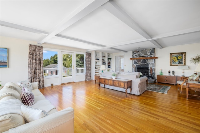 living room featuring light hardwood / wood-style flooring, beam ceiling, and a fireplace