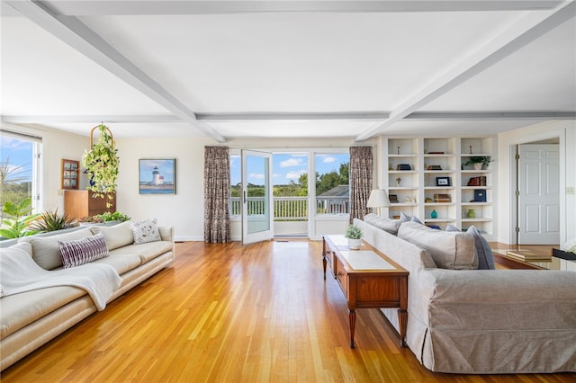 living room featuring beamed ceiling, light hardwood / wood-style flooring, and a healthy amount of sunlight