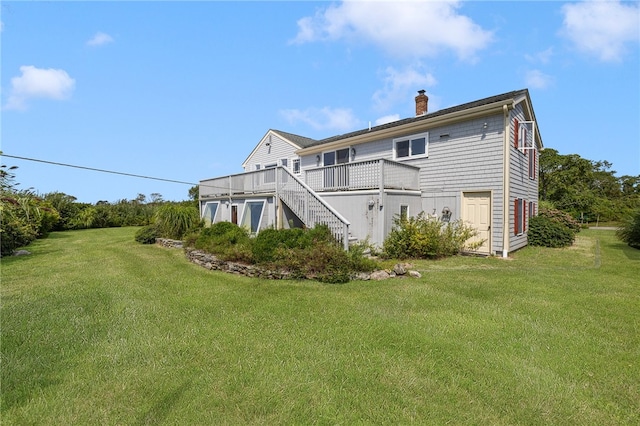 back of property featuring a lawn and a wooden deck