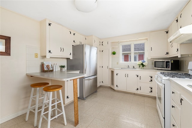 kitchen with white cabinetry, tasteful backsplash, light tile patterned floors, stainless steel appliances, and a breakfast bar area