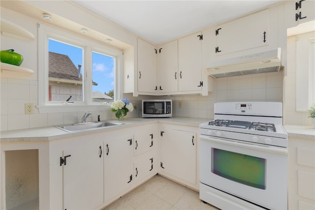 kitchen with white cabinets, backsplash, light tile patterned floors, white gas range, and sink