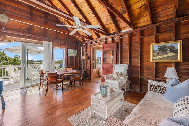 living room with wooden walls, hardwood / wood-style floors, wood ceiling, beamed ceiling, and ceiling fan