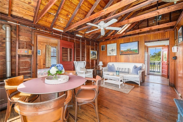 dining space featuring wood walls, dark hardwood / wood-style floors, wooden ceiling, and vaulted ceiling with beams