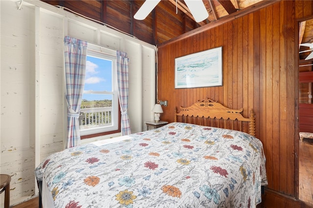 bedroom with ceiling fan, wood walls, and lofted ceiling with beams