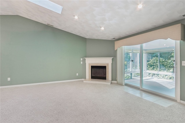 unfurnished living room featuring a fireplace, lofted ceiling with skylight, and light colored carpet