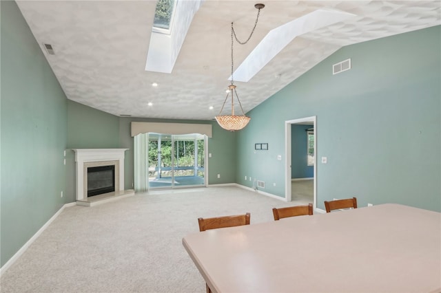 carpeted dining room with lofted ceiling with skylight and a premium fireplace