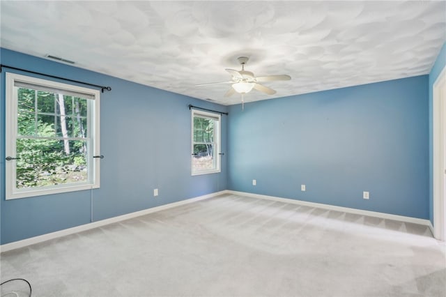 spare room featuring a healthy amount of sunlight, ceiling fan, and carpet