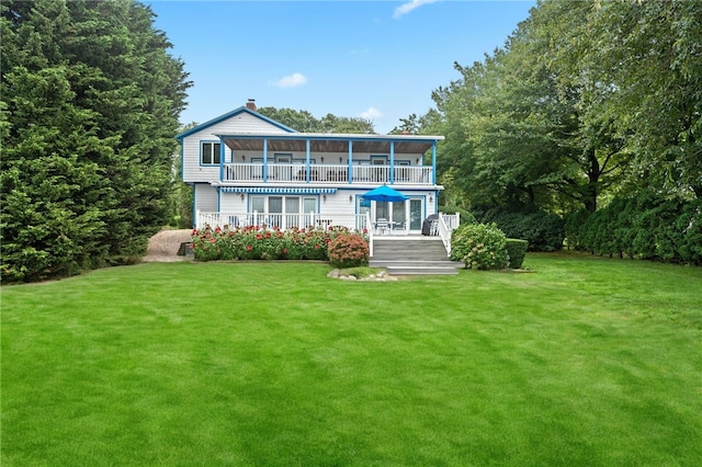 back of house with a balcony and a yard