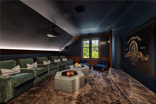 home theater featuring vaulted ceiling, wooden walls, and carpet floors