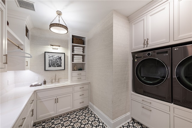 laundry room featuring cabinets, washer and clothes dryer, and sink