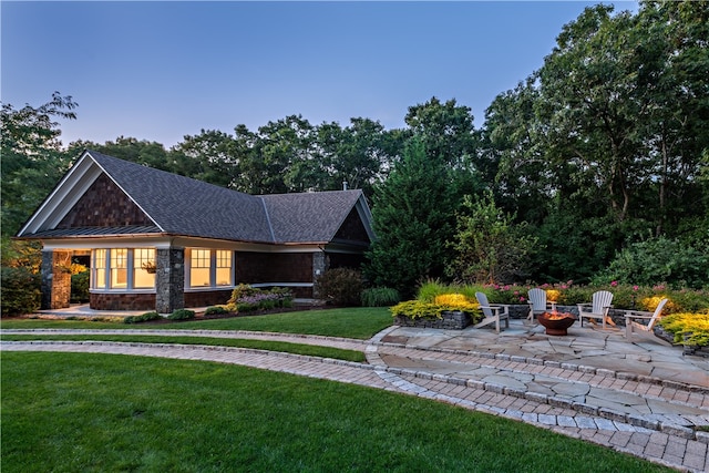 view of front of property featuring a lawn, a patio area, and a fire pit