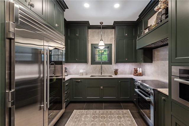 kitchen with decorative light fixtures, backsplash, green cabinets, high quality appliances, and sink