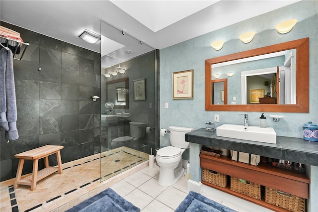 bathroom with tile patterned flooring, tiled shower, vanity, and toilet