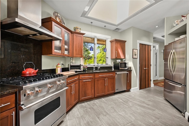 kitchen featuring tasteful backsplash, dark stone countertops, sink, wall chimney range hood, and appliances with stainless steel finishes