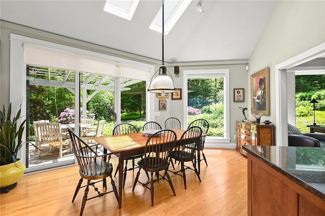 dining space featuring lofted ceiling with skylight and light hardwood / wood-style floors