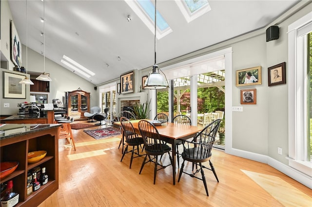 dining room with a skylight, light wood-type flooring, high vaulted ceiling, and sink