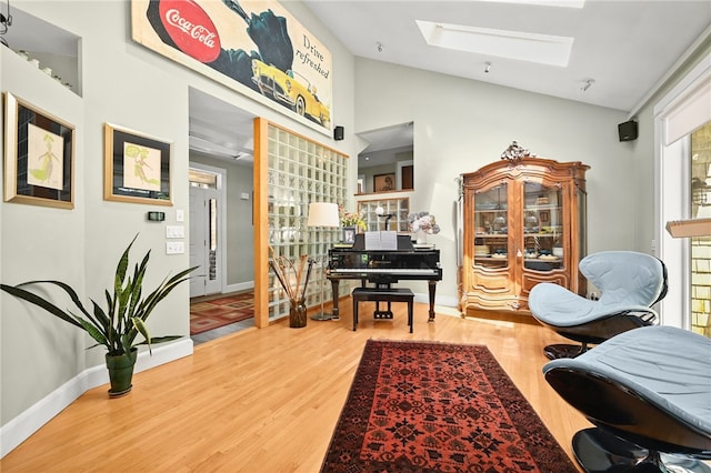 living area featuring hardwood / wood-style flooring and vaulted ceiling with skylight