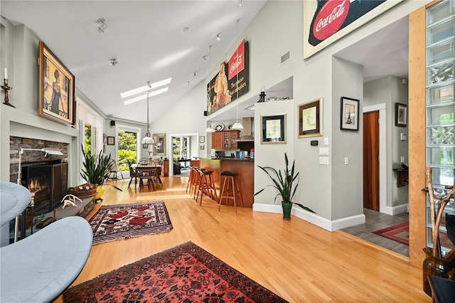 living room featuring wood-type flooring, a skylight, and high vaulted ceiling