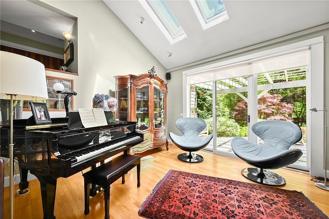 misc room with wood-type flooring, a skylight, and high vaulted ceiling