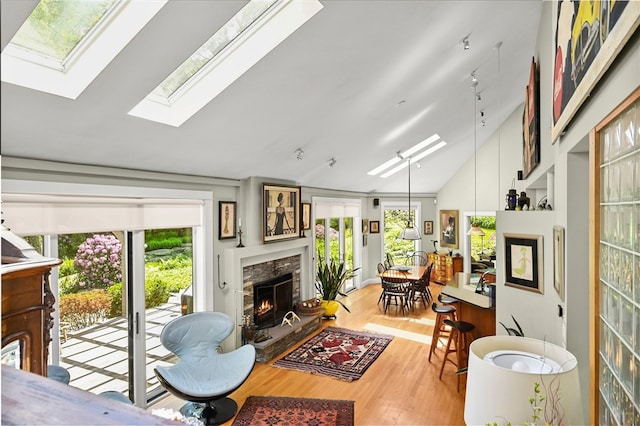 living room with vaulted ceiling with skylight, hardwood / wood-style floors, and a healthy amount of sunlight