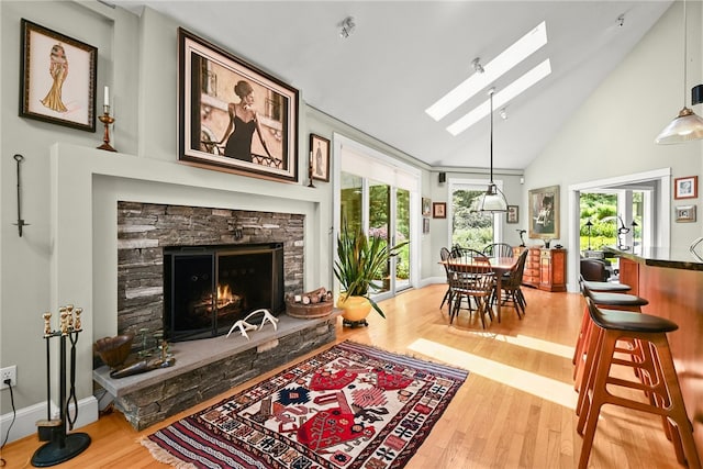 living room featuring a fireplace, a skylight, hardwood / wood-style floors, and high vaulted ceiling