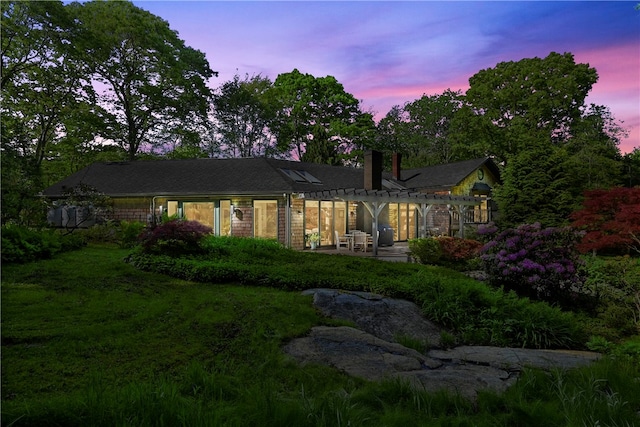 back house at dusk with a lawn