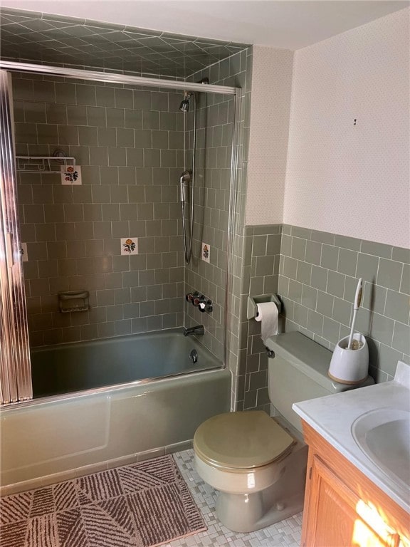 full bathroom featuring enclosed tub / shower combo, tile patterned floors, toilet, tile walls, and vanity