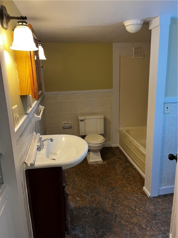 bathroom with vanity, toilet, and tile walls