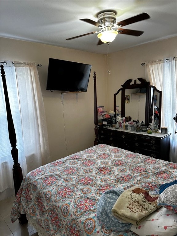 bedroom featuring ceiling fan, tile patterned floors, and multiple windows