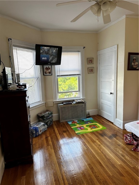 interior space with dark wood-type flooring, ceiling fan, and ornamental molding