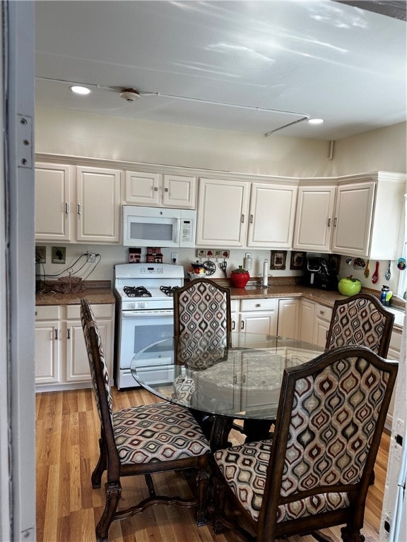 kitchen featuring light wood-type flooring, white cabinets, and white appliances