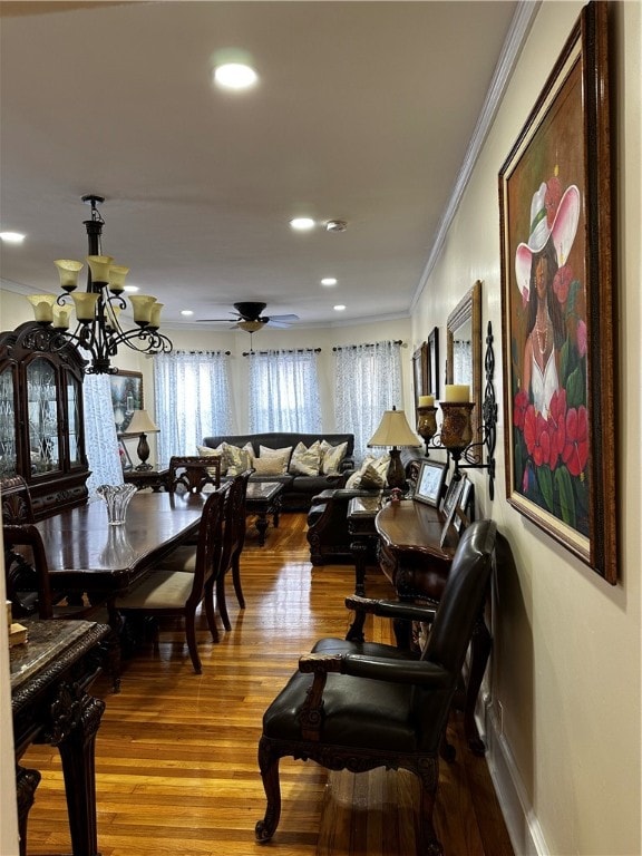 dining room featuring hardwood / wood-style floors, ceiling fan with notable chandelier, and ornamental molding