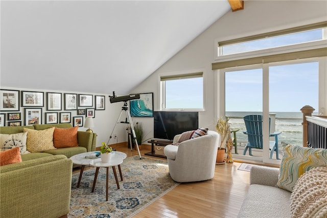 living room featuring high vaulted ceiling, light wood-type flooring, and beam ceiling