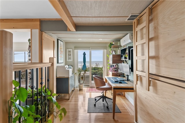 home office with light hardwood / wood-style flooring, beam ceiling, and a wall mounted air conditioner