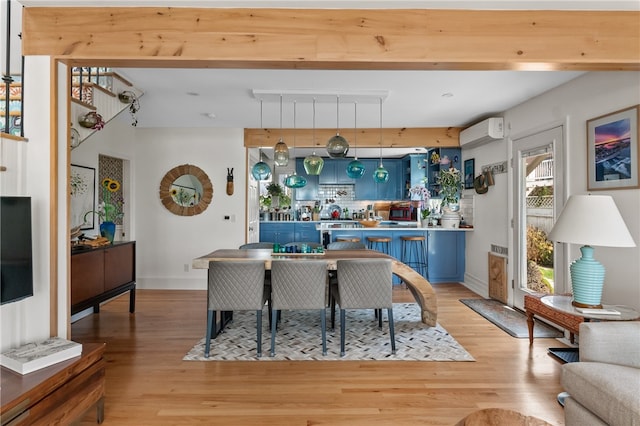 kitchen with light hardwood / wood-style floors, blue cabinetry, and a wall mounted air conditioner