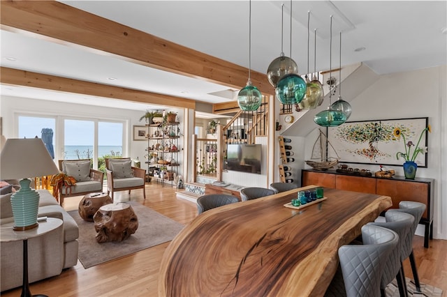 dining area featuring light wood-type flooring and beam ceiling