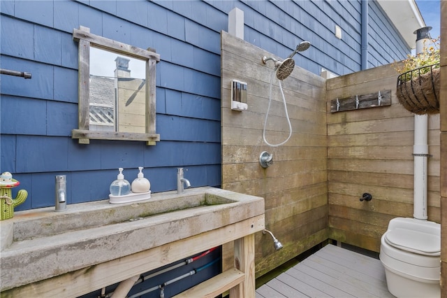 bathroom with walk in shower, wooden walls, toilet, and vanity