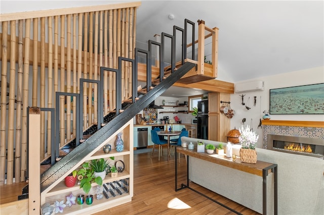 stairs with wood-type flooring, a wall unit AC, and a tile fireplace