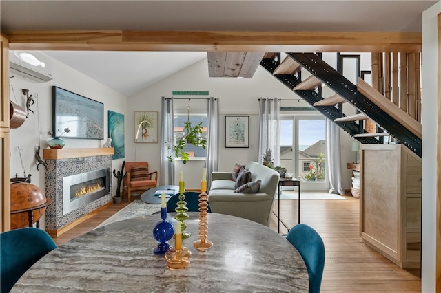 dining space featuring an AC wall unit, light wood-type flooring, vaulted ceiling with beams, and a fireplace