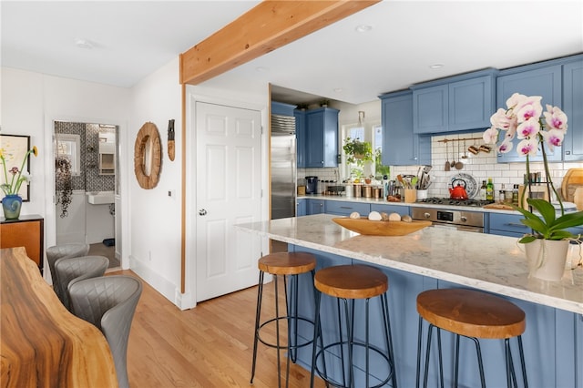 kitchen with blue cabinets, light wood-type flooring, and tasteful backsplash