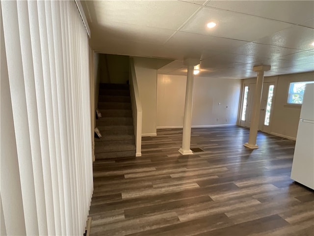 basement featuring dark hardwood / wood-style floors, white fridge, and a drop ceiling