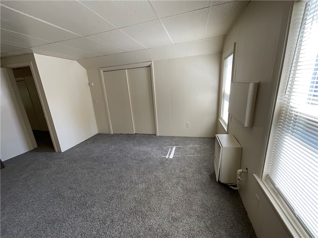 unfurnished bedroom with a closet, carpet flooring, and a paneled ceiling