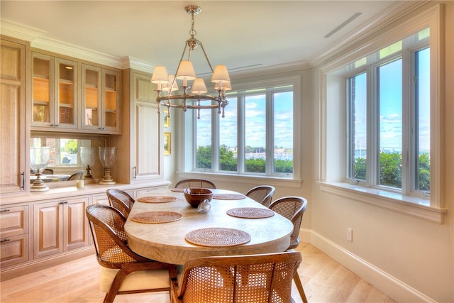 dining area featuring light wood-type flooring, a chandelier, and ornamental molding