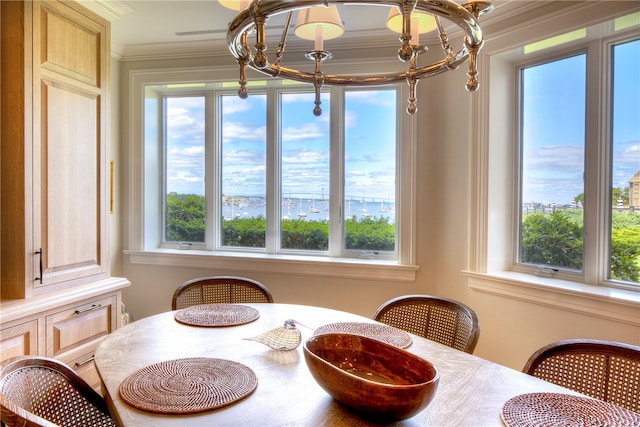 dining space featuring ornamental molding, a healthy amount of sunlight, an inviting chandelier, and a water view