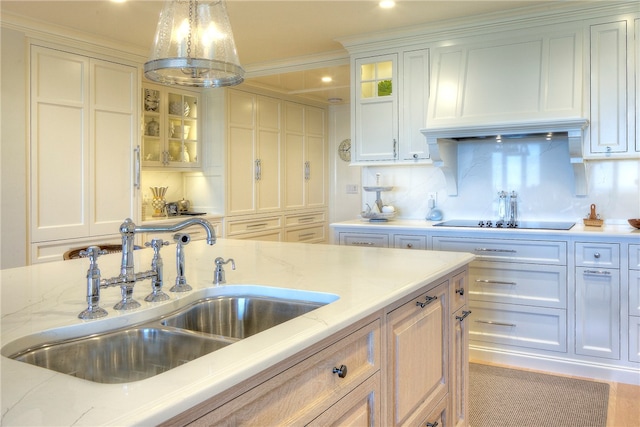 kitchen with pendant lighting, ornamental molding, sink, light stone counters, and white cabinets