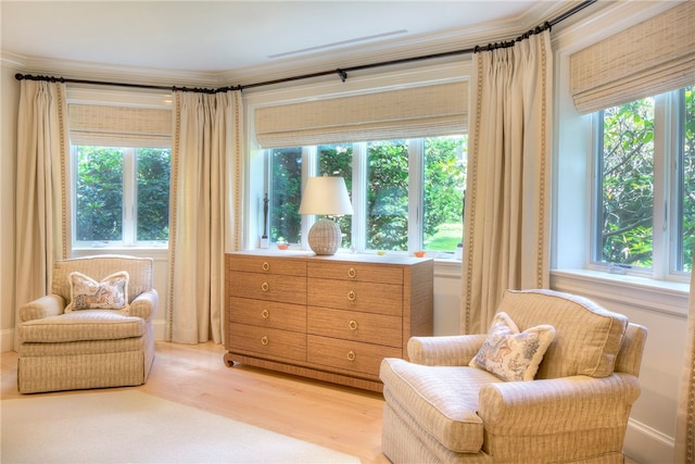 sitting room with crown molding and light hardwood / wood-style flooring